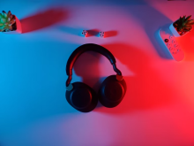 A pair of black wireless headphones on a table with blue and red lighting